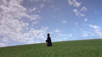 Movie still from “Toys” (1992), directed by Barry Levinson – A person standing in the middle of a green field; Extreme Wide shot, Low angle