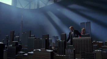 Movie still from “Toys” (1992), directed by Barry Levinson – Two people standing on top of a building in front of a city skyline; Extreme Wide shot, Low angle