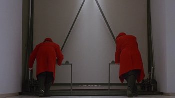 Movie still from “Toys” (1992), directed by Barry Levinson – Two men in red coats are looking at a mirror; Wide shot, Low angle