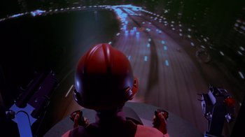 Movie still from “Toys” (1992), directed by Barry Levinson – A person wearing a helmet is riding on a roller coaster at night; Wide shot, High angle