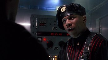 Movie still from “Toys” (1992), directed by Barry Levinson – A man wearing a uniform and a hat in front of a control panel; Close Up shot, Low angle