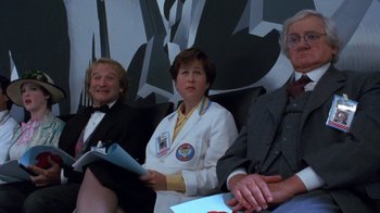 Movie still from “Toys” (1992), directed by Barry Levinson – A group of people sitting next to each other; Medium shot, Low angle