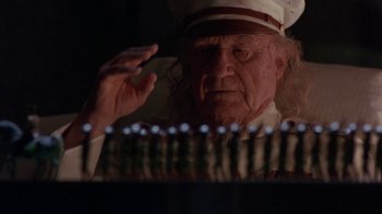 Movie still from “Toys” (1992), directed by Barry Levinson – An old man wearing a white hat is looking at candles in the dark; Close Up shot, Low angle