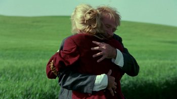 Movie still from “Toys” (1992), directed by Barry Levinson – Two people hugging each other in a grassy field; Medium shot, Low angle