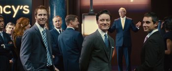 Movie still from “Trance” (2013), directed by Danny Boyle – A group of men standing next to each other in suits; Medium shot, Over the shoulder angle