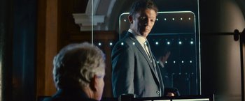 Movie still from “Trance” (2013), directed by Danny Boyle – A man standing in front of a mirror in a suit; Medium shot, Over the shoulder angle