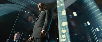 Movie still from “Trance” (2013), directed by Danny Boyle – A man in a suit standing in front of a mirror; Medium shot, Low angle