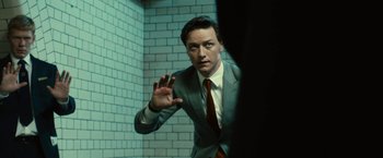 Movie still from “Trance” (2013), directed by Danny Boyle – A man wearing a suit and tie in a room; Medium shot, Low angle