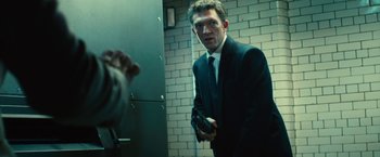 Movie still from “Trance” (2013), directed by Danny Boyle – A man wearing a suit and tie holding a cell phone; Medium shot, Low angle