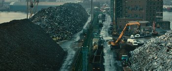 Movie still from “Trance” (2013), directed by Danny Boyle – A large pile of garbage next to a road; Extreme Wide shot, High angle
