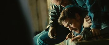 Movie still from “Trance” (2013), directed by Danny Boyle – A man leaning on a window ledge while another man holds a cigarette; Close Up shot, Over the shoulder angle