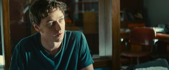 Movie still from “Trance” (2013), directed by Danny Boyle – A man sitting at a table in front of a window; Close Up shot, Over the shoulder angle
