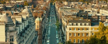 Movie still from “Trance” (2013), directed by Danny Boyle – An aerial view of a city street with cars parked on the side; Extreme Wide shot, High angle