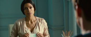 Movie still from “Trance” (2013), directed by Danny Boyle – A woman holding a piece of paper while sitting at a table; Close Up shot, Over the shoulder angle