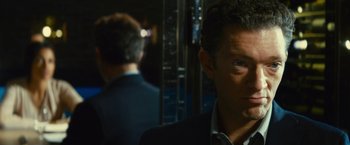 Movie still from “Trance” (2013), directed by Danny Boyle – A man in a suit and tie standing next to another man in a suit and tie; Close Up shot, Over the shoulder angle