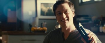 Movie still from “Trance” (2013), directed by Danny Boyle – A young man smiling for the camera in a kitchen; Close Up shot, Over the shoulder angle