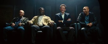 Movie still from “Trance” (2013), directed by Danny Boyle – Two men sitting in chairs in the dark; Medium shot, Low angle