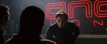 Movie still from “Trance” (2013), directed by Danny Boyle – A man is talking to another man in front of a neon sign; Medium shot, Over the shoulder angle