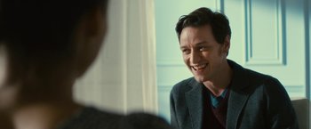 Movie still from “Trance” (2013), directed by Danny Boyle – A man in a suit and tie smiling for a picture; Close Up shot, Over the shoulder angle