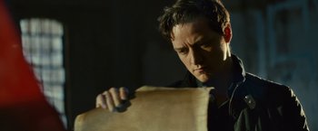 Movie still from “Trance” (2013), directed by Danny Boyle – A man holding a piece of paper in front of his face; Close Up shot, Low angle