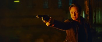 Movie still from “Trance” (2013), directed by Danny Boyle – A man is holding a gun in the dark; Close Up shot, Low angle