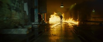 Movie still from “Trance” (2013), directed by Danny Boyle – A person walking on a street near a fire; Wide shot, Low angle