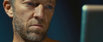 Movie still from “Trance” (2013), directed by Danny Boyle – A man with a beard and blue eyes; Extreme Close Up shot, Low angle