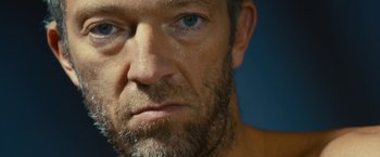 Movie still from “Trance” (2013), directed by Danny Boyle – A man with a beard and blue eyes; Extreme Close Up shot, Low angle