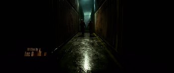 Movie still from “Transporter 3” (2008), directed by Olivier Megaton – Two people are walking down a dark hallway; Extreme Wide shot, High angle