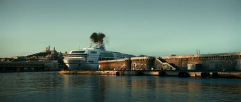 Movie still from “Transporter 3” (2008), directed by Olivier Megaton – A large cruise ship is docked in the harbor; Extreme Wide shot, Low angle