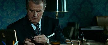 Movie still from “Transporter 3” (2008), directed by Olivier Megaton – An older man wearing a suit and tie looking at a cell phone; Close Up shot, Low angle