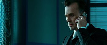 Movie still from “Transporter 3” (2008), directed by Olivier Megaton – A person wearing a suit holding a cell phone; Close Up shot, Low angle