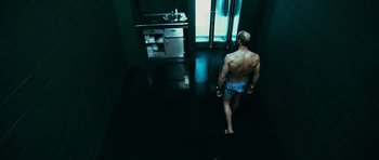 Movie still from “Transporter 3” (2008), directed by Olivier Megaton – A man walking in a kitchen with no shirt on; Wide shot, Low angle