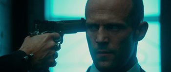 Movie still from “Transporter 3” (2008), directed by Olivier Megaton – A bald man with a gun in his hand; Close Up shot, Low angle