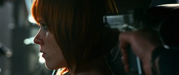 Movie still from “Transporter 3” (2008), directed by Olivier Megaton – A woman with short red hair is cutting her hair with an electric hair trimmer; Close Up shot, Over the shoulder angle