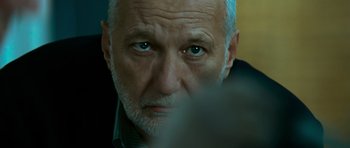 Movie still from “Transporter 3” (2008), directed by Olivier Megaton – An older man with blue eyes stares into the camera; Close Up shot, Over the shoulder angle
