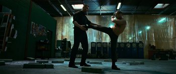 Movie still from “Transporter 3” (2008), directed by Olivier Megaton – A man kicking another man in a boxing ring; Wide shot, Low angle
