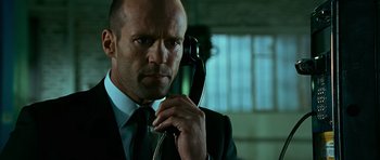 Movie still from “Transporter 3” (2008), directed by Olivier Megaton – A man in a suit and tie holding a phone to his ear; Close Up shot, Low angle
