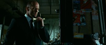 Movie still from “Transporter 3” (2008), directed by Olivier Megaton – A man in a suit and tie talking on a phone; Close Up shot, Low angle