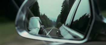 Movie still from “Transporter 3” (2008), directed by Olivier Megaton – A view from a car of a road with trees in the background; Close Up shot, Low angle