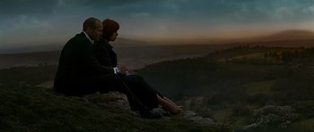 Movie still from “Transporter 3” (2008), directed by Olivier Megaton – A man and a woman sitting on top of a hill; Wide shot, Low angle