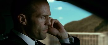 Movie still from “Transporter 3” (2008), directed by Olivier Megaton – A man in a suit talking on a phone; Close Up shot, Low angle