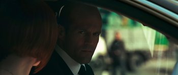 Movie still from “Transporter 3” (2008), directed by Olivier Megaton – A man in a suit and tie looking out of a car window; Close Up shot, Over the shoulder angle