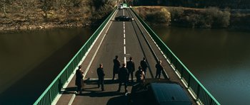 Movie still from “Transporter 3” (2008), directed by Olivier Megaton – A group of people standing on the side of a bridge; Extreme Wide shot, High angle