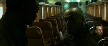 Movie still from “Transporter 3” (2008), directed by Olivier Megaton – Two men are sitting on a train looking at each other; Close Up shot, Over the shoulder angle