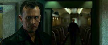 Movie still from “Transporter 3” (2008), directed by Olivier Megaton – A man standing on a train looking into the camera; Close Up shot, Low angle