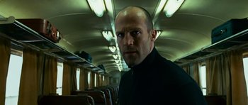 Movie still from “Transporter 3” (2008), directed by Olivier Megaton – A man with a bald head standing on a train; Close Up shot, Low angle