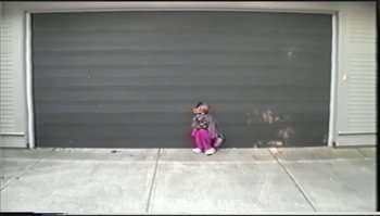 Movie still from “Trash Humpers” (2009), directed by Harmony Korine – A person sitting on the ground with a camera; Extreme Wide shot, High angle