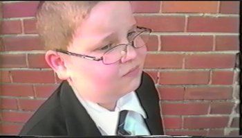 Movie still from “Trash Humpers” (2009), directed by Harmony Korine – A boy in a suit and tie wearing glasses; Extreme Close Up shot, High angle