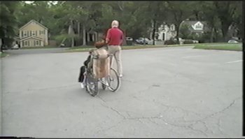 Movie still from “Trash Humpers” (2009), directed by Harmony Korine – A man riding a bike down the middle of the street; Extreme Wide shot, High angle